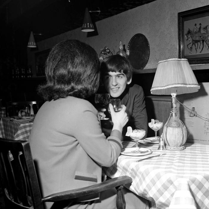 Beatle George Harrison sits at a restaurant table with his date in 1964 