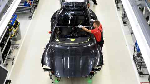 An employee of German car producer Porsche works on a Porsche Taycan electric sports car at the assembly line in Stuttgart, southwestern Germany