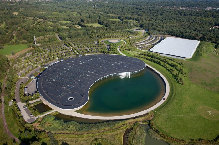 The centre seen from the air, in the shape of a yin-yang symbol, one half steel and glass building, the other a man-made lake  