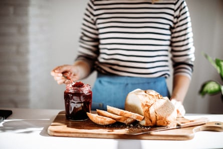 Closeup of woman making toast with jam