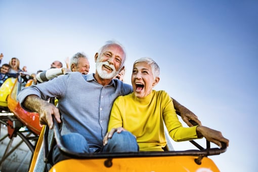 Carefree seniors having fun on rollercoaster at amusement park