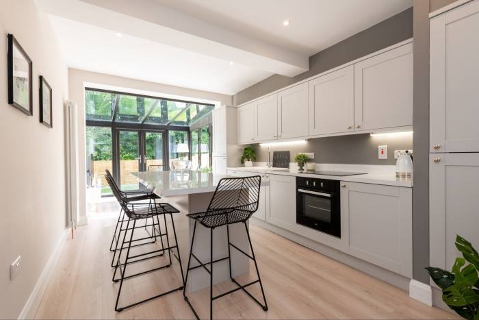 A bright, modern white and grey kitchen with open-plan flow through to the conservatory