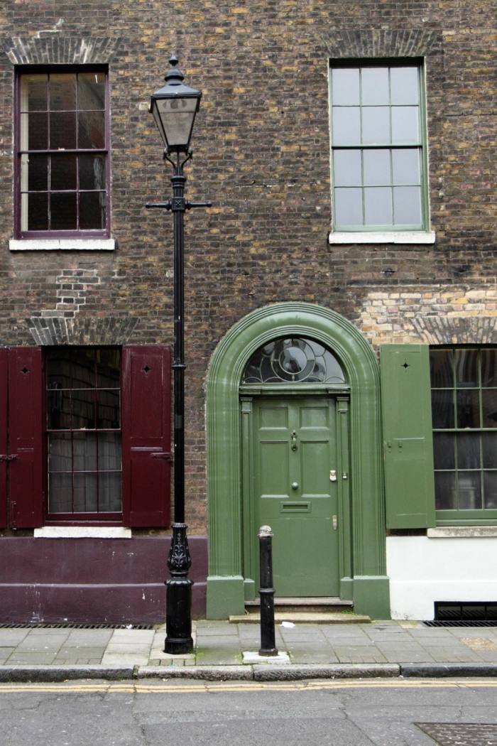 A green door, and next door a window with red-brown shutters