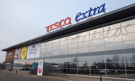 The exterior of a modern Tesco Extra store with a long plate glass facade and the store sign mounted in freestanding letters on the roof