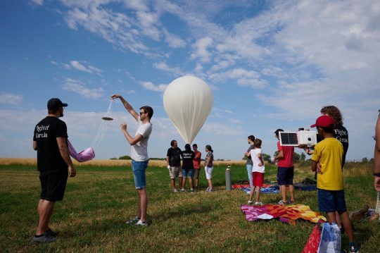 A family were stunned to find a UFO landed in their garden - and discovered it was a lost space balloon from Germany. Charlotte and Allen Buckley woke to see the 7ft long out-of-the-world object bouncing across their garden. And they carefully inspected to find it was a white box attached to a balloon with cameras fitted. The couple checked the marking to discover it was made by space company Solenix 560 miles away - and was lost in their garden in the countryside. It travelled from Darmstadt in Germany to Welsh countryside near the market town of Llanfair Caereinion in Powys. Pictured here is the launch of the balloon WALES NEWS SERVICE