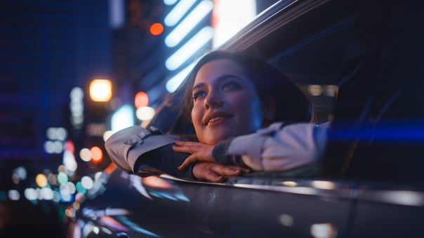 Happy person leaning out of a car window while riding at night