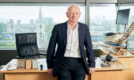 Howard Davies in his office in dark suit and open-neck shirt