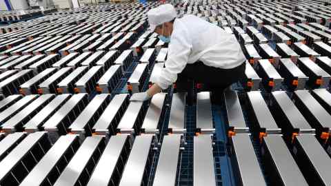 A worker examines car batteries at a factory in China