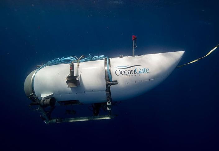 The Titan submersible, a white cylindrical vessel with a rounded front that has a single porthole, diving in dark waters.