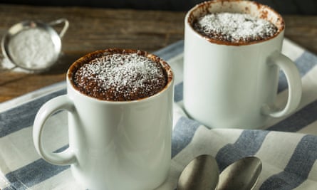 Two mugs on a bench containing microwave chocolate brownies.