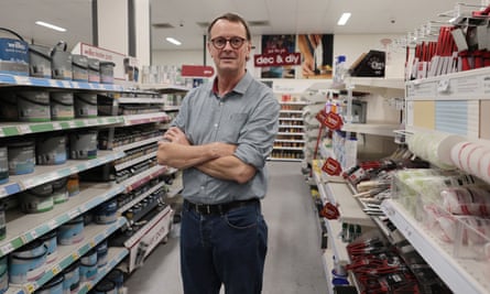 A man stands in the middle of a store, arms folded