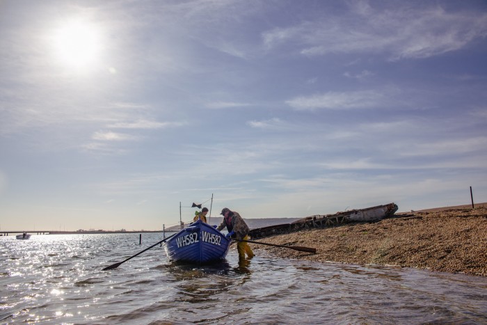 Fishermen stand with their boat on the shoreline
