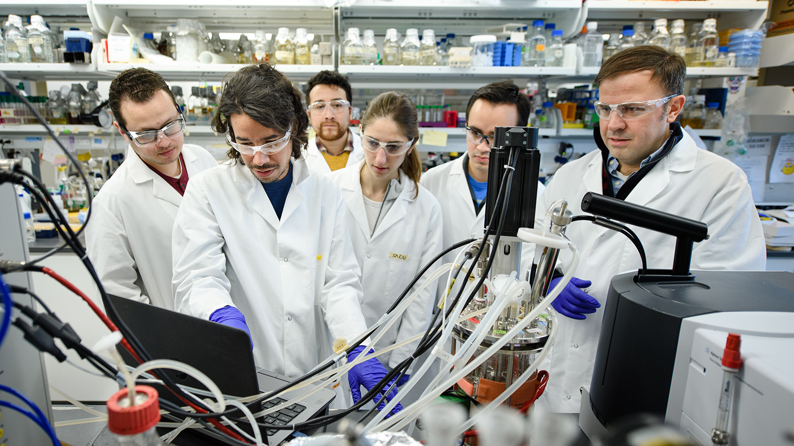 Group of researchers gathered around computer screen in a lab.