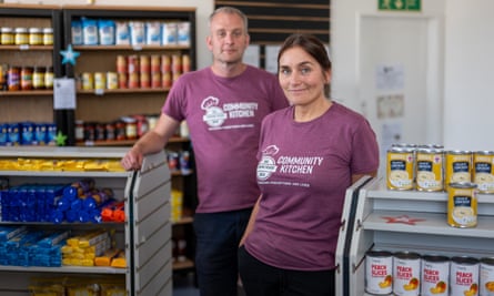 Alan Tilley and June Mills stand between food shelves