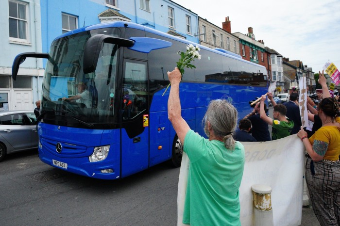 Locals wave as a coach carrying asylum seekers arrives in Portland