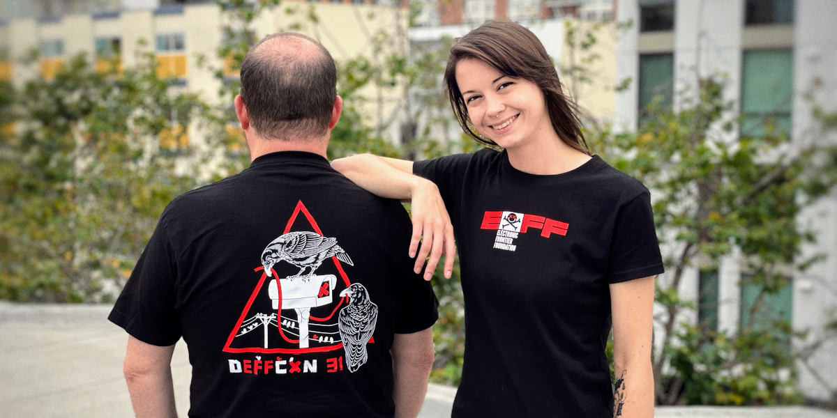 Two people in black shirts with ravens in a red triangle