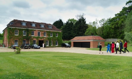 The eight Selling Super Houses agents walk on a gravel drive past a garage and towards a big ivy-covered house