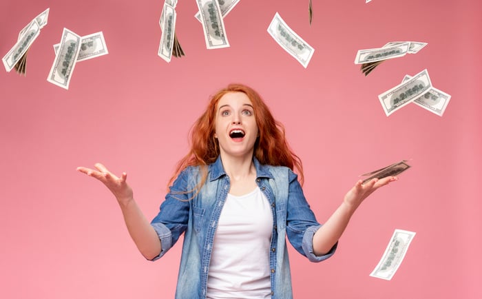 A person catches cash as it falls from the sky.