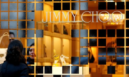 The window of a Jimmy Choo shop, with a single pair of high heels framed by a decorative window design and the Jimmy Choo logo