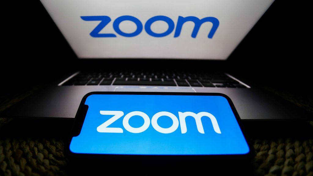 Zoom logos are seen displayed on a laptop and a phone screens in this illustration photo