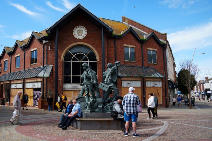 People sit beneath a statue in Barrow town centre