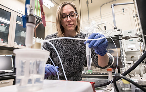 A researcher working in a lab with lab equipment.