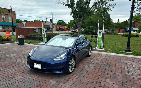 Electric vehicle charging at a station in a rural town.