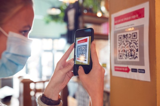 Woman In Mask With Mobile Phone Checking Into Venue Scanning QR Code During Health Pandemic