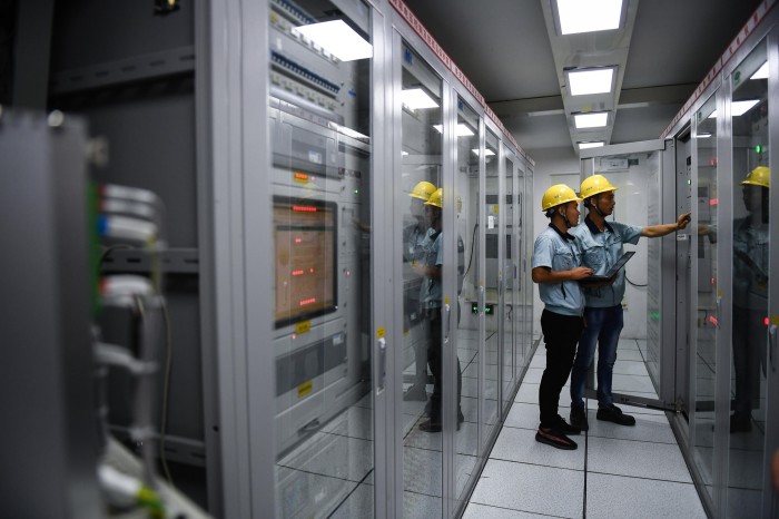 Two people standing on a hallway with electronic equipment on both sides