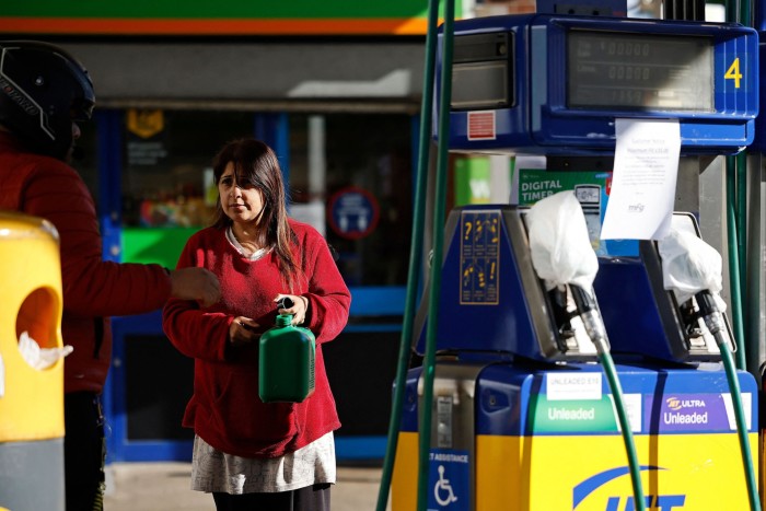 A woman holds a petrol can in Leyton, east London