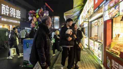 Shoppers pass food stalls at a night market in China