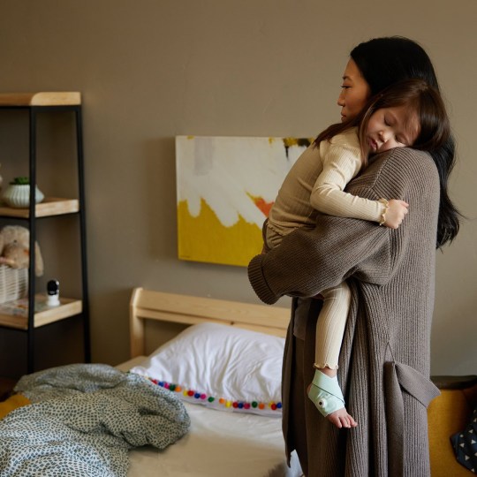 Child being carried while wearing Owlet sock