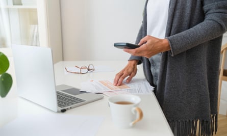 Woman with financial bills using a calculator and a laptop at a table