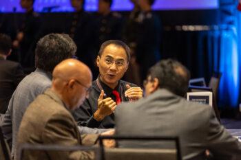 A photo of conference attendees talking at a table.