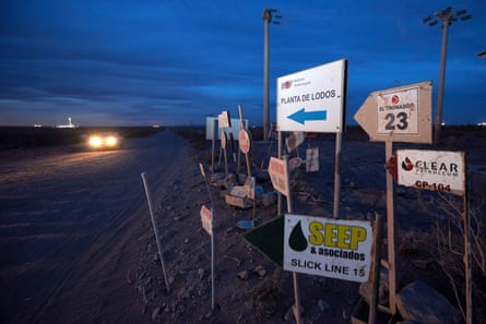 Signs for energy companies on a roadside at dusk 