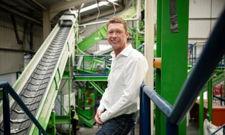 Roberts standing in front of a large green piece of machinery, next to an elevating conveyor belt 