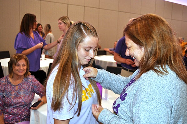 Ann Carole Bryan ’68, right, watches as her granddaughter, Emma Grace Bunting, receives a legacy pin from her mother, Krista Williams Bunting ’01. (Photo by Patricia Earnhardt Tyndall)