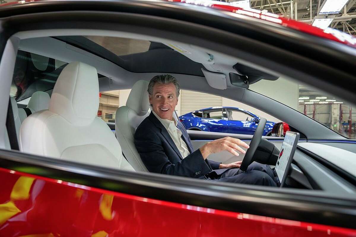 Newsom checks out a Tesla during a factory tour on the final day of his visit to China.