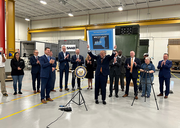 15 people standing in a semi-circle, some clapping