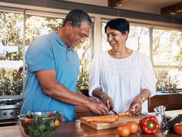 Mature, couple and healthy cooking in kitchen to chop vegetables for salad diet, nutrition and lunch meal at home. Happy man, woman and help cut carro