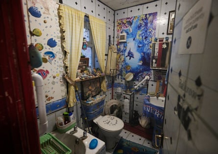 A cluttered and stained bathroom, with black mould in the ceiling