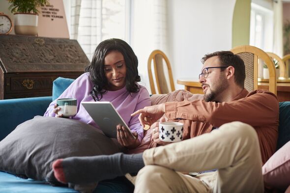 Couple sitting on sofa assessing finances