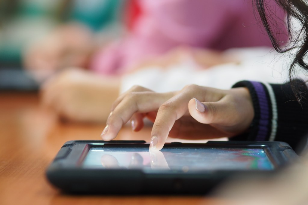 A kid taps on a tablet.