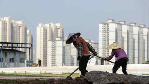 Workers in front of residential buildings under construction at the Phoenix Palace project, in Heyuan, Guangdong province, China