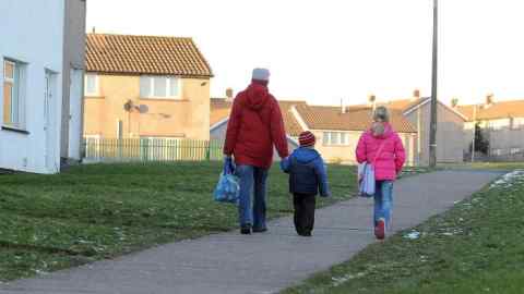 People walk on a pavement on a housing estate in Merthyr Tydfil, South Wales