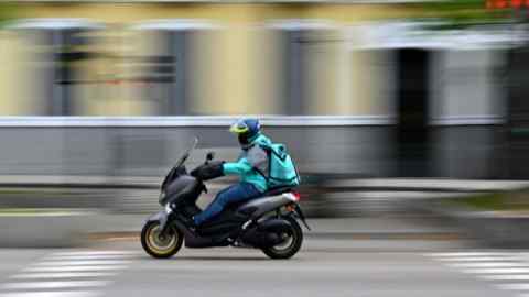 A Deliveroo rider on a motorbike in Madrid