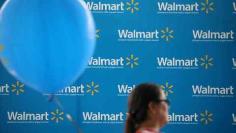 A woman posses the Walmart logo outside one of its stores