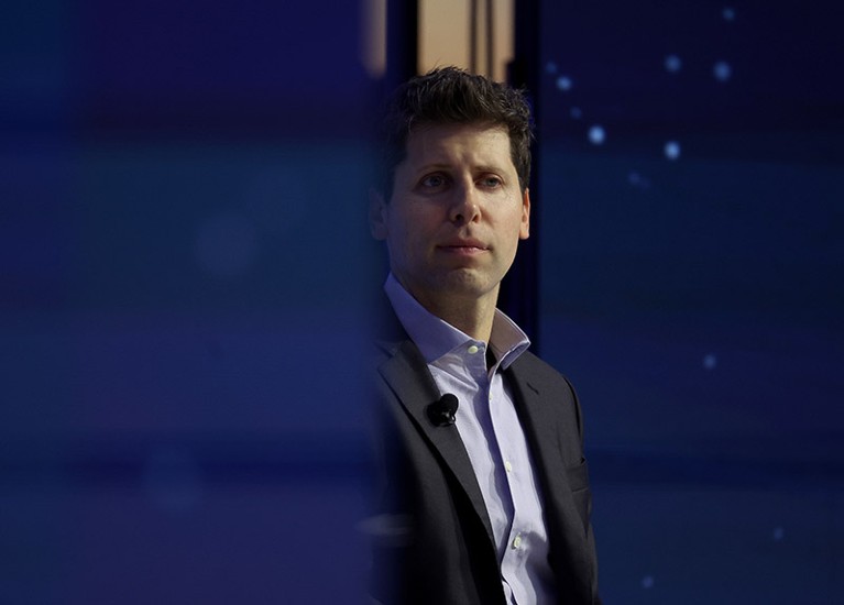 Sam Altman seen through a gap in two blue boards.