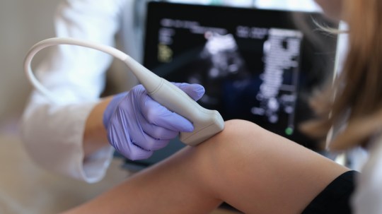 Doctor conducting ultrasound examination of knee joint in child closeup