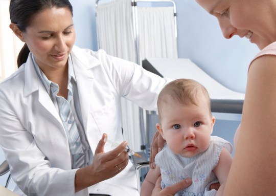 Baby girl (3-5 months) having vaccine injected in arm with syringe